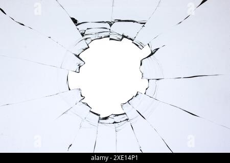 Loch im Glas, gebrochenes Fenster mit Rissstruktur. Die Wirkung von gebrochenem transparentem Glas. Stockfoto