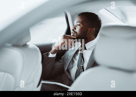 Geschäftsmann In Grauem Anzug, Der Während Der Fahrt Im Auto Nachdenkt Stockfoto
