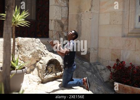 Nigerianischer Mann, Muslim, zum Pfingstchristentum konvertiert, kniet auf dem Felsen der Qualen im Garten Gethsemane und betet überschwänglich mit Händen und Gesicht nach oben Stockfoto