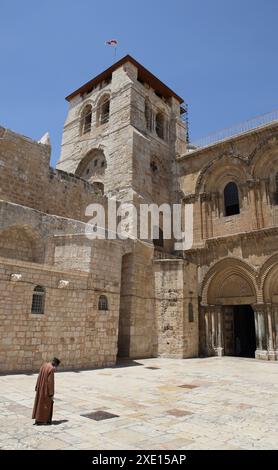 Der äthiopische Mönch verbeugt und meditiert im Gebet vor dem Haupteingang der Grabeskirche oder der Auferstehungskirche. Stockfoto