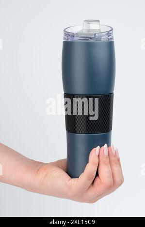 Blaue Thermoflasche in der Hand isoliert auf weißem Studiohintergrund, Vorderansicht Stockfoto