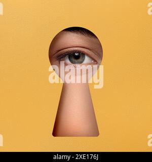 Frau, die durch das Schlüsselloch in goldener Oberfläche schaut Stockfoto