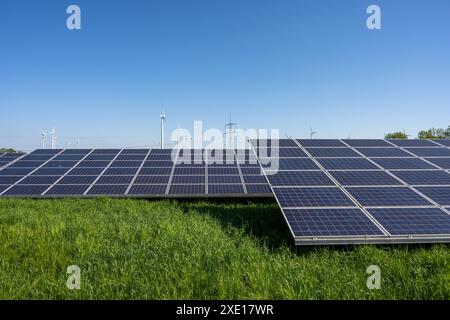 Solaranlage mit Stromleitungen und Windturbinen im Hintergrund, wie man sie in Deutschland sieht Stockfoto