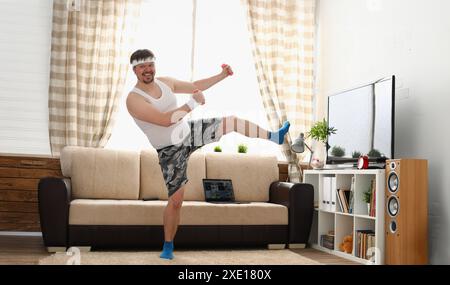 Der dicke Mann in Sportbekleidung und Kurzhanteln macht körperliche Bewegung Stockfoto