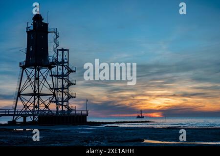 Der Leuchtturm von Obereversand und der Angelschneider auf der offenen Meereslandschaft bei Sonnenuntergang. Silhouette des HIS Stockfoto