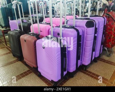 Viele neue mehrfarbige große Kunststoffkoffer auf Rädern. Konzept von Reisen, Urlaub, Tourismus. Stockfoto