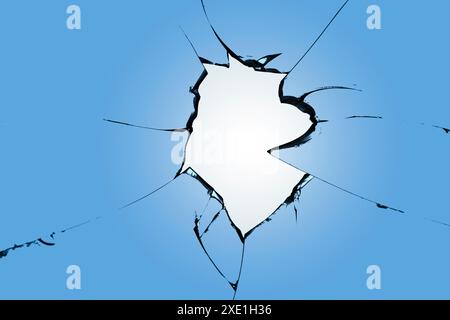 Risse auf dem blauen Glas, ein kaputtes Fenster nach dem Beschuss. Die Wirkung der Zerstörung beim Beschuss Stockfoto