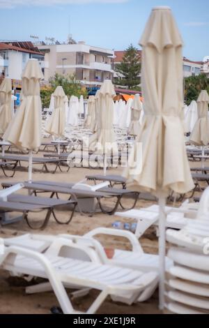Sonnenschirme und Sonnenliegen im zusammengesetzten Zustand am Strand. Stockfoto