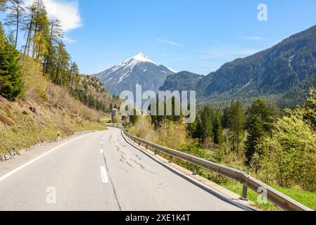 Leere gewundene Bergstraße durch ein bewaldetes Tal an einem klaren Frühlingstag Stockfoto