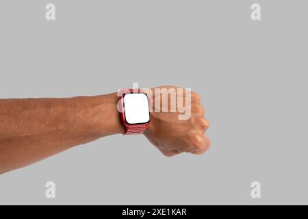 Männliche Hand, die eine rote Smartwatch trägt, isoliert auf grauem Hintergrund, blanker Bildschirm Stockfoto