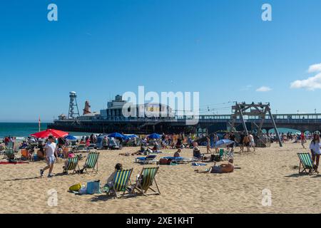 East Cliff Beach, Bournemouth, Großbritannien - 23. Juni 2024: Sonnenanbeter in Liegestühlen neben dem PierZip Beach Tower vor dem Bournemouth Pier. Stockfoto