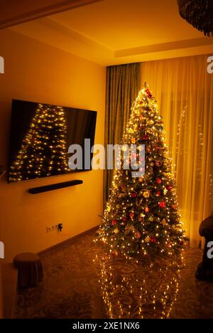 Weihnachtsbaum dekoriert mit Lichtern in gemütlicher Inneneinrichtung. Stockfoto