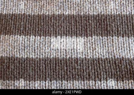 Eine Nahaufnahme eines Strickstoffs mit abwechselnden Streifen in hell- und dunkelgrün. Die warmen, erdigen Töne und die einladende Textur des Strickpults machen einen Eindruck Stockfoto
