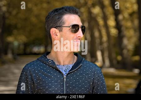 Mediterraner Mann in lässiger Sportbekleidung und Sonnenbrille, seitliches Porträt im Freien. Stockfoto