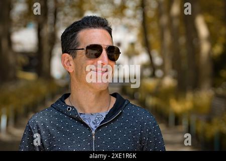 Mediterraner Mann in lässiger Sportkleidung und Sonnenbrille, lächelnd. Stockfoto
