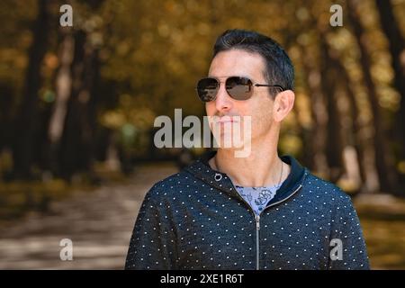 Mediterraner Mann in lässiger Sportbekleidung und Sonnenbrille, seitliches Porträt im Freien. Stockfoto