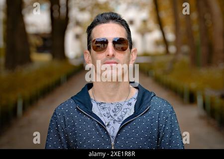 Mediterraner Mann in lässiger Sportbekleidung und Sonnenbrille, Frontporträt, fokussierte Haltung. Stockfoto