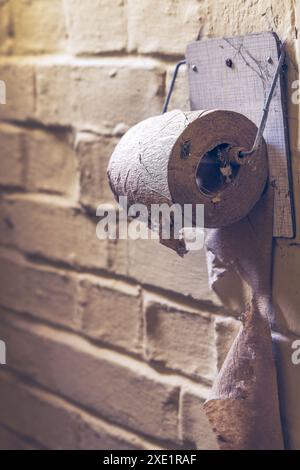 Ein alter Toilettenpapierhalter in einem baufälligen Haus Stockfoto