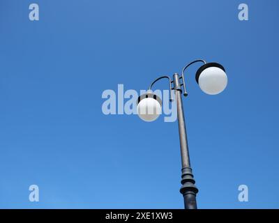 Lampenmast mit runden Glühbirnen auf blauem Himmel Hintergrund. Stockfoto