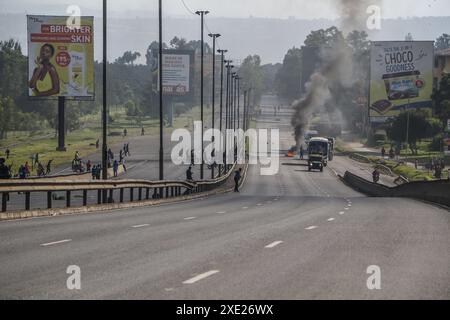 Nakuru, Kenia. Juni 2024. Die Fahrzeuge fahren an einem Lagerfeuer auf der Hauptstraße Nairobi-Nakuru vorbei, während der landesweiten Demonstrationen gegen die vorgeschlagenen Steuern im Finance Bill 2024 in Nakuru Town. Mehrere Tote und viele Verletzte wurden gemeldet, nachdem die Polizei das Feuer für die Demonstranten eröffnet hatte. Quelle: SOPA Images Limited/Alamy Live News Stockfoto