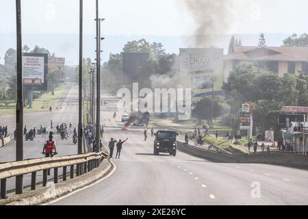 Nakuru, Kenia. Juni 2024. Die Fahrzeuge fahren an einem Lagerfeuer auf der Hauptstraße Nairobi-Nakuru vorbei, während der landesweiten Demonstrationen gegen die vorgeschlagenen Steuern im Finance Bill 2024 in Nakuru Town. Mehrere Tote und viele Verletzte wurden gemeldet, nachdem die Polizei das Feuer für die Demonstranten eröffnet hatte. Quelle: SOPA Images Limited/Alamy Live News Stockfoto