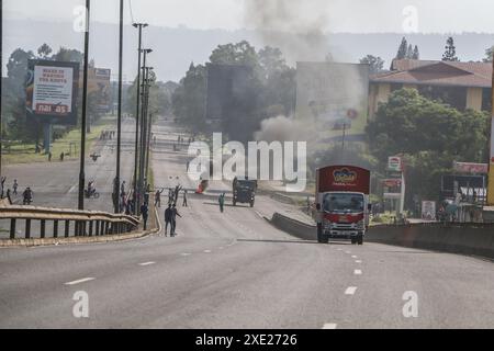 Nakuru, Kenia. Juni 2024. Die Fahrzeuge fahren an einem Lagerfeuer auf der Hauptstraße Nairobi-Nakuru vorbei, während der landesweiten Demonstrationen gegen die vorgeschlagenen Steuern im Finance Bill 2024 in Nakuru Town. Mehrere Tote und viele Verletzte wurden gemeldet, nachdem die Polizei das Feuer für die Demonstranten eröffnet hatte. Quelle: SOPA Images Limited/Alamy Live News Stockfoto