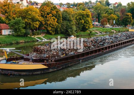 Transportindustrie. Schiffskahn transportiert Schrott und Sand mit Kies. Der mit Metallschrott beladene Lastkahn ist auf der Straße Stockfoto