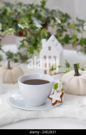 Tasse Tee mit hausgemachten Keksen, dekorativen Häusern und Kürbissen Stockfoto