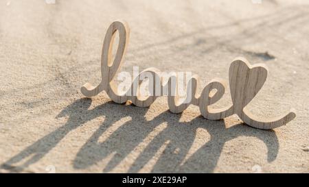 Hölzerne Wort Love auf Sandstrand Hintergrund. Konzept des romantischen Feiertags, Vorschlag, Valentinstag Grußkarte, Pos. Stockfoto