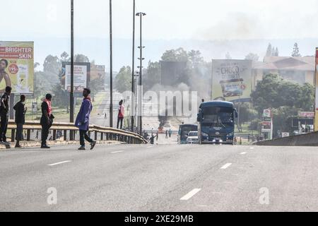 Nakuru, Kenia. Juni 2024. Die Fahrzeuge fahren an einem Lagerfeuer auf der Hauptstraße Nairobi-Nakuru vorbei, während der landesweiten Demonstrationen gegen die vorgeschlagenen Steuern im Finance Bill 2024 in Nakuru Town. Mehrere Tote und viele Verletzte wurden gemeldet, nachdem die Polizei das Feuer für die Demonstranten eröffnet hatte. (Foto: James Wakibia/Sopa Images/SIPA USA) Credit: SIPA USA/Alamy Live News Stockfoto