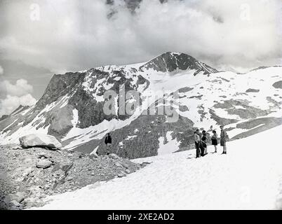 1950er Jahre, historisch, eine kleine Gruppe von Wanderern, die auf einem verschneiten Berg hoch oben in den schweizer alpen stehen. Stockfoto