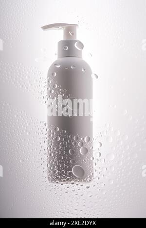Eine Flasche Duschgel, Shampoo oder Körpercreme auf dem Hintergrund von Tropfen. Stockfoto