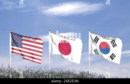 Amerikanische Flagge mit japanischer Flagge und südkoreanischer Flagge am bewölkten Himmel. Im Himmel winken Stockfoto