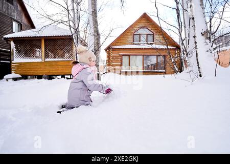 Eine Familie baut im Winter einen Schneemann aus weißem Schnee auf dem Hof. Stockfoto