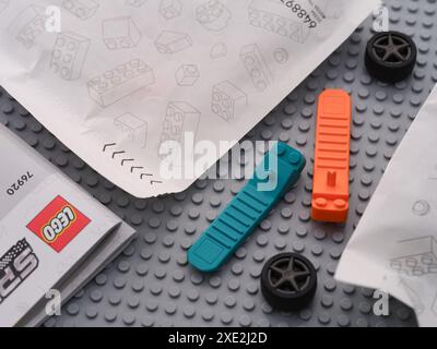 Tambow, Russische Föderation - 22. Juni 2024 Lego-Ziegeltrenner und Räder liegen zwischen Anweisungen und Papiertüten mit Lego-Stücken auf einem grauen Becken Stockfoto