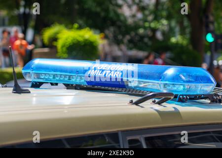Blaue blinkende Lichterleiste auf einem Sicherheitsauto mit den Worten MILITÄRPOLIZEI auf Spanisch vor einem Hintergrund von verschwommenen Menschen und Laub in der Stadt Stockfoto