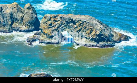 Fliegen Sie durch den Arch Rock mit stürzenden Wellen an der Küste von Oregon Stockfoto