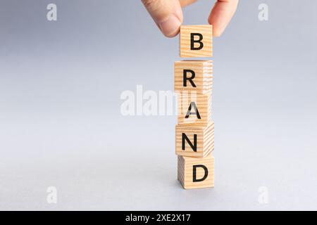 Holzwürfel mit der Hand anordnen, um das MARKENWORT zu buchstabieren. Kopierbereich Stockfoto