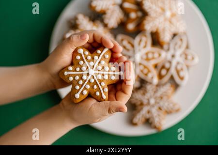 Ingwerweiskekse in Kinderhänden auf dem Hintergrund des Weihnachtsbaums. Stockfoto