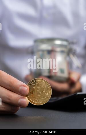 Erfahrene Händlerzeiger zeigen digitales Gold der Bitcoin-Münze nach dem Zählen von Einkommens-Banknoten in Euro-Bargeld auf dem Rechner. Nahaufnahme von ha Stockfoto