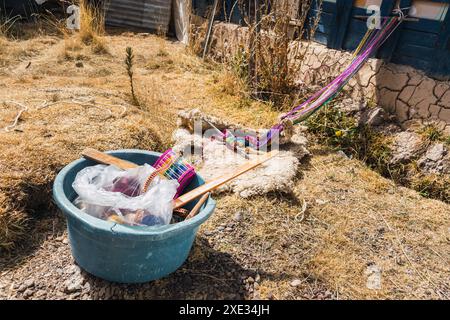 Gurt aus Alpakasfaser, die an einem sonnigen Tag auf dem Boden liegen und von Webinstrumenten begleitet werden Stockfoto