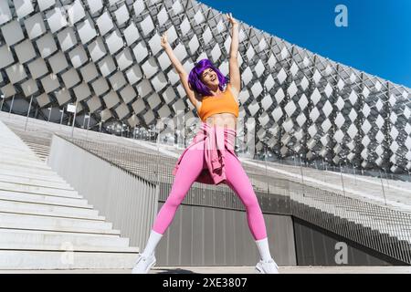 Sorglose aktive Tänzerin in farbenfroher Sportkleidung, die Spaß auf der Straße hat Stockfoto