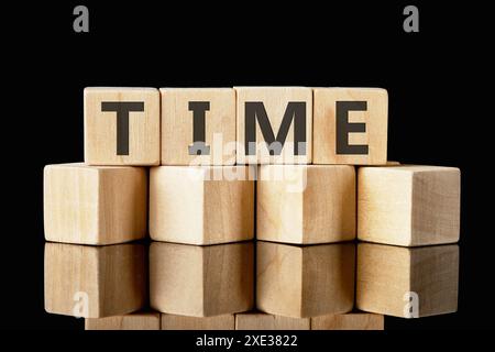 GESCHÄFTSKONZEPT. ZEITBUCHSTABEN aus Holzwürfeln auf einem glänzenden schwarzen Hintergrund Stockfoto