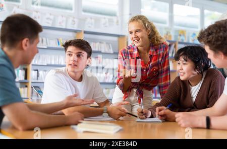 Gruppenporträt lächelnder Jugendkinder, die in der Bibliothek zusammenarbeiten Stockfoto