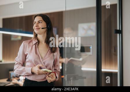 Selbstbewusste junge Geschäftsfrau mit Headset in moderner Büroumgebung Stockfoto