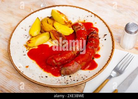 Würstchen mit Kartoffelscheiben in Tomatensoße Stockfoto