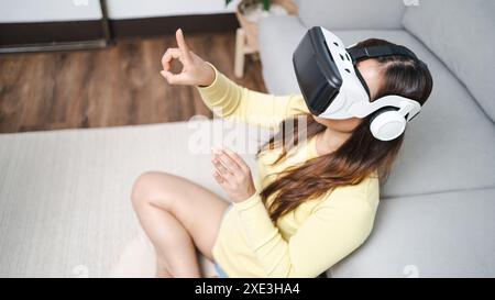 Junge asiatische Frau, die während des VR Experience Future Technology Konzepts virtuelle Realität in Berührung bringt. Stockfoto