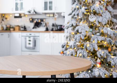 Runder leerer Tisch zur Demonstration des Produkts mit Platz für Text in weißer Küche, moderner Innenraum mit Tannenbaum und fai Stockfoto