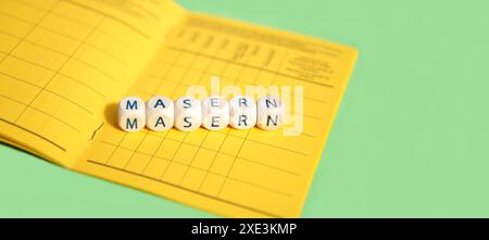 Masern, dargestellt als Holzwürfel auf dem Hintergrund des deutschen Impfzertifikats, dieses Symbol Stockfoto