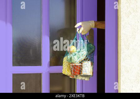 Heimlieferung einiger Lebensmittel bei Quarantäne der Coronavirus-Infektion COVID-19. Die Hand des Menschen nimmt Stockfoto